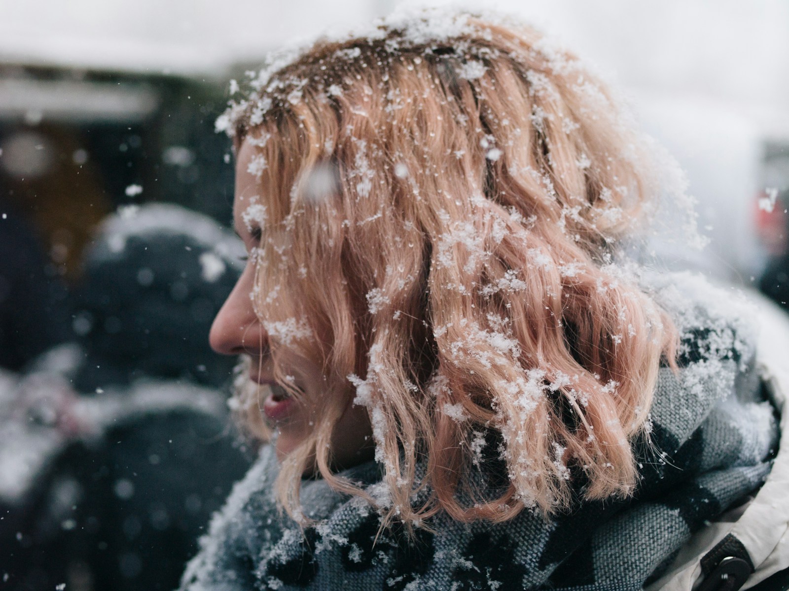 a woman standing in the snow with her hair blowing in the wind